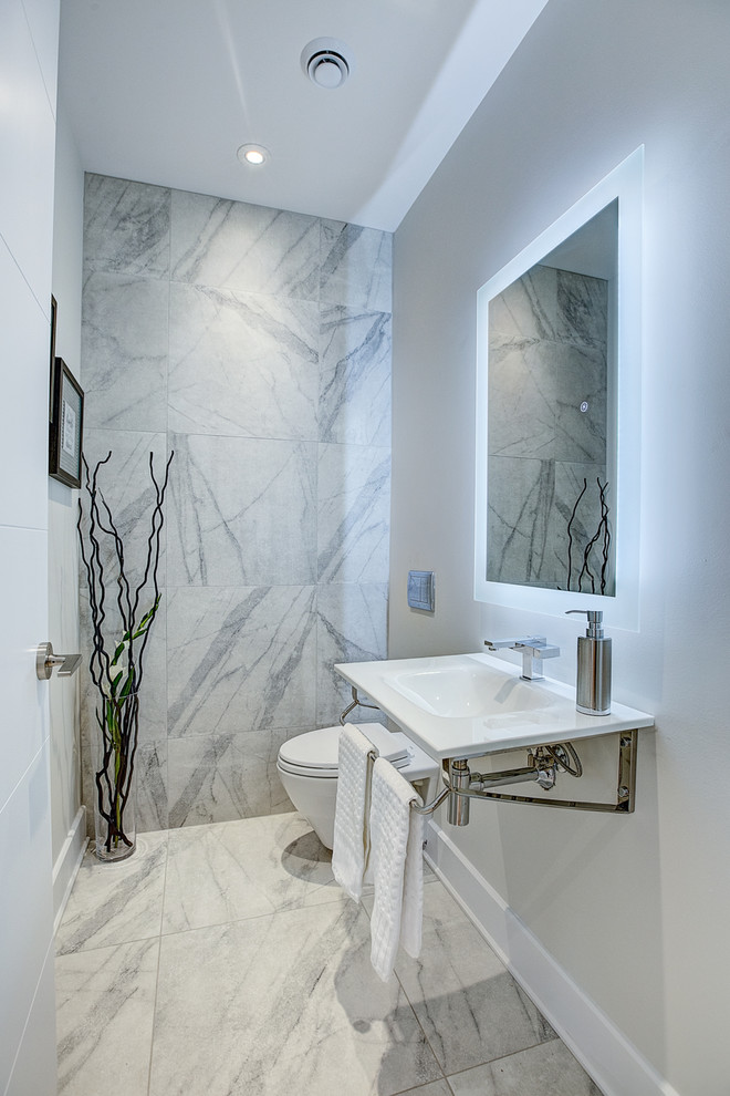 Modern cloakroom in Montreal with a one-piece toilet, white tiles, ceramic tiles, white walls, a wall-mounted sink, white floors and porcelain flooring.