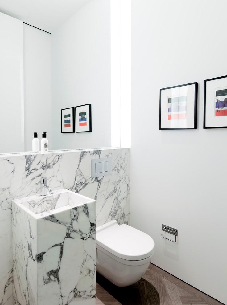 Immagine di un piccolo bagno di servizio design con lavabo integrato, WC sospeso, pareti bianche, parquet scuro, piastrelle di marmo, piastrelle bianche e top in marmo