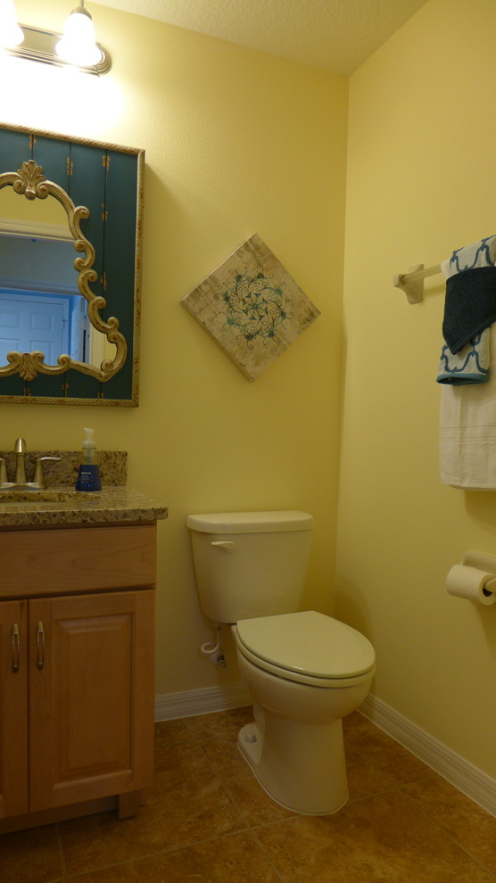 Immagine di un bagno di servizio eclettico con lavabo sottopiano, ante con bugna sagomata, ante in legno chiaro, top in granito e WC a due pezzi