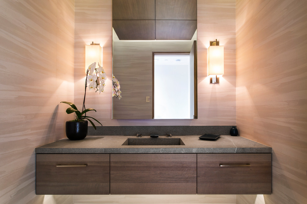 Moderne Gästetoilette mit flächenbündigen Schrankfronten, dunklen Holzschränken, brauner Wandfarbe, integriertem Waschbecken und grauer Waschtischplatte in Orange County