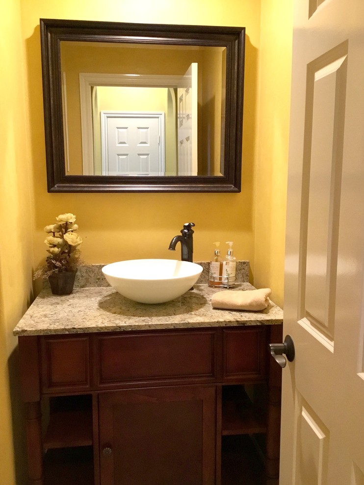 Mediterrane Gästetoilette mit gelber Wandfarbe, Aufsatzwaschbecken, Schrankfronten mit vertiefter Füllung, dunklen Holzschränken, Toilette mit Aufsatzspülkasten und Granit-Waschbecken/Waschtisch in Orange County