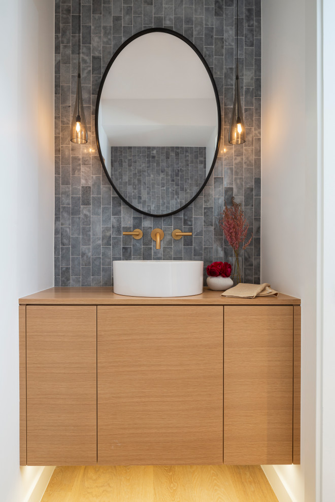 Design ideas for a small contemporary cloakroom in Denver with flat-panel cabinets, light wood cabinets, a one-piece toilet, multi-coloured tiles, marble tiles, white walls, light hardwood flooring, a vessel sink, wooden worktops, beige floors, brown worktops and a floating vanity unit.