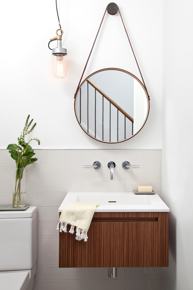 Cette image montre un petit WC et toilettes design en bois foncé avec un lavabo intégré, un placard à porte plane, un carrelage gris, des carreaux de céramique, un mur blanc et WC séparés.