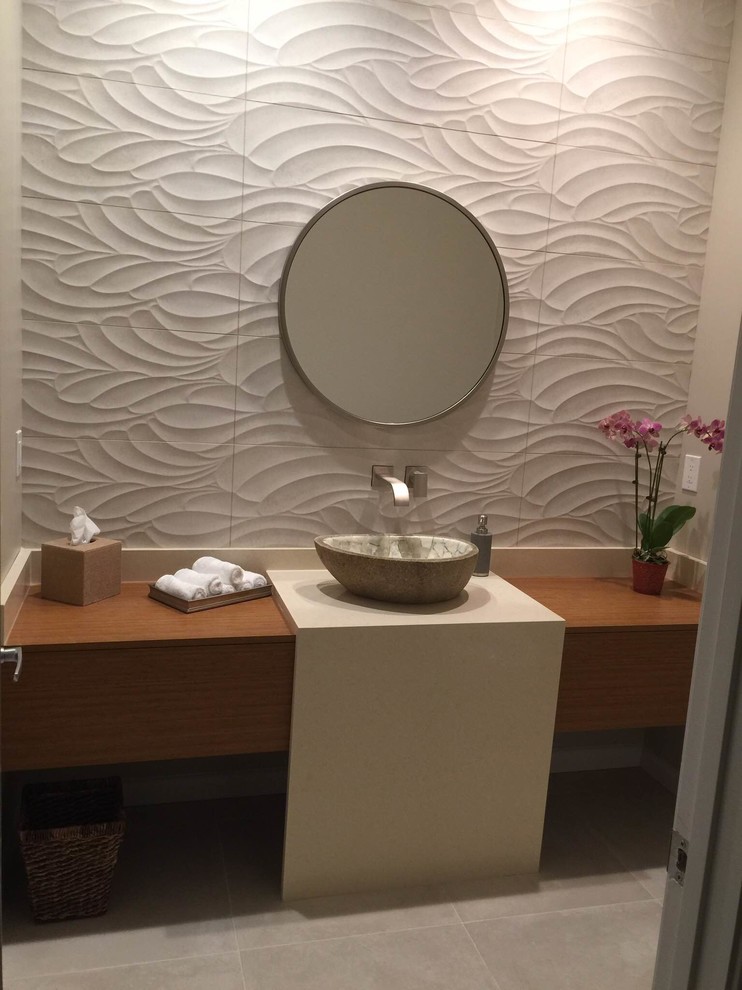 Mid-sized trendy gray tile and porcelain tile porcelain tile and beige floor powder room photo in Hawaii with flat-panel cabinets, medium tone wood cabinets, a one-piece toilet, beige walls, a vessel sink, quartz countertops and beige countertops