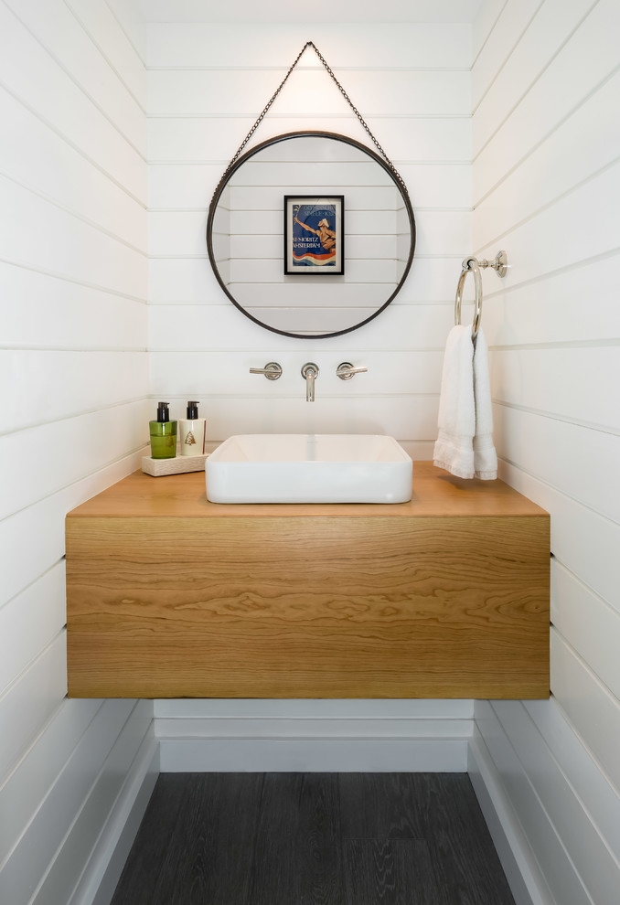 Diseño de aseo campestre pequeño con paredes blancas, suelo de madera oscura, lavabo sobreencimera, encimera de madera, suelo marrón y encimeras marrones
