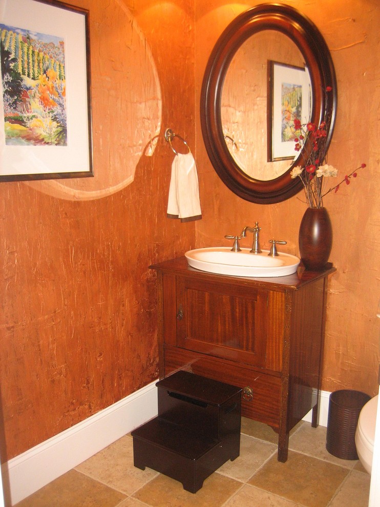 Mittelgroße Mediterrane Gästetoilette mit Schrankfronten mit vertiefter Füllung, dunklen Holzschränken, oranger Wandfarbe, Travertin, Einbauwaschbecken, Waschtisch aus Holz, braunem Boden und brauner Waschtischplatte in Raleigh