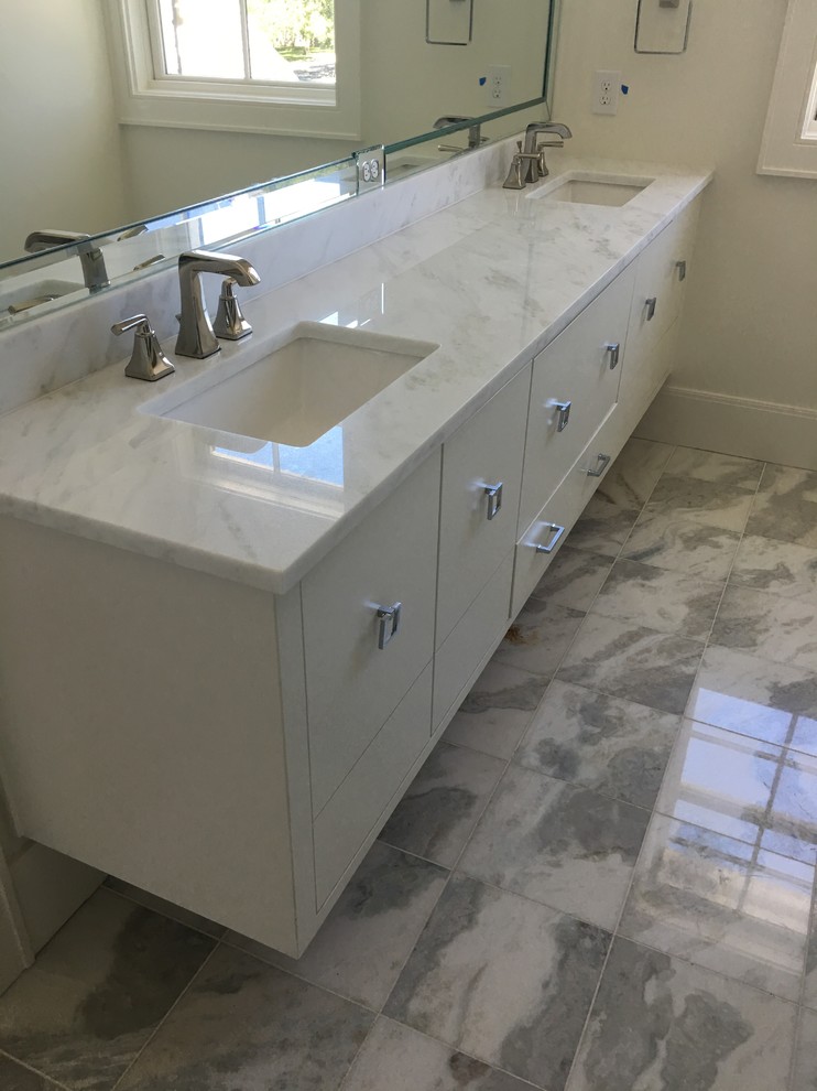 This is an example of a medium sized modern cloakroom in Dallas with recessed-panel cabinets, white cabinets, a two-piece toilet, white walls, cement flooring, a submerged sink, marble worktops, grey floors and white worktops.