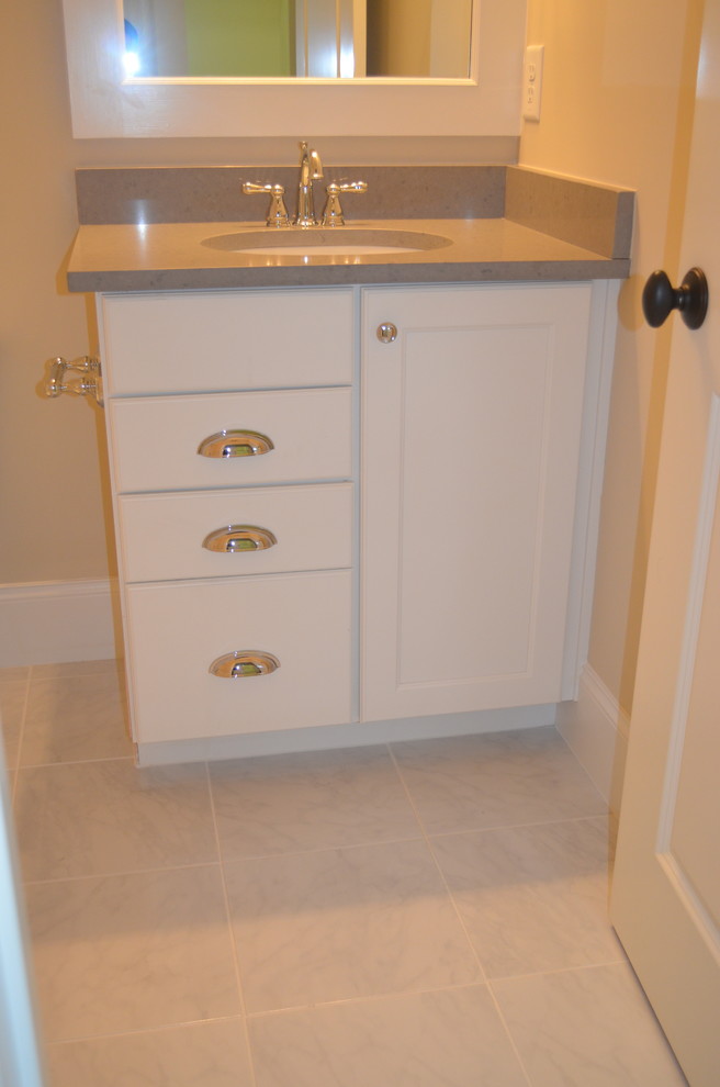 Inredning av ett klassiskt mellanstort toalett, med luckor med infälld panel, vita skåp, beige väggar, marmorgolv, ett undermonterad handfat och grått golv
