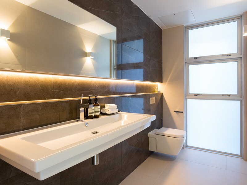 Esempio di un bagno di servizio moderno con WC sospeso, piastrelle in gres porcellanato, pavimento in gres porcellanato, pareti marroni e lavabo rettangolare