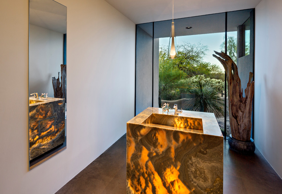 Inspiration for a southwestern concrete floor and gray floor powder room remodel in Phoenix with white walls, a pedestal sink and onyx countertops