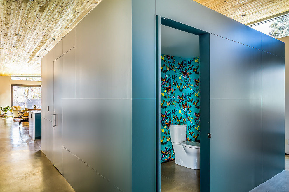 Moderne Gästetoilette mit flächenbündigen Schrankfronten, grünen Schränken, Wandtoilette mit Spülkasten, bunten Wänden, Betonboden und grauem Boden in Denver