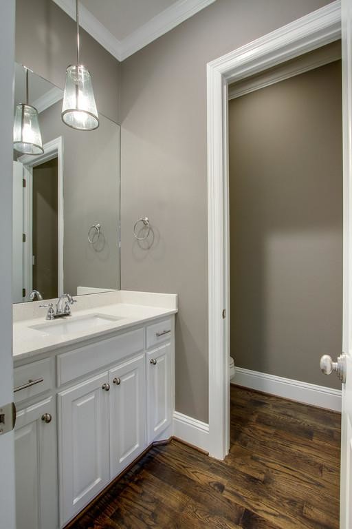 ダラスにある小さなトランジショナルスタイルのおしゃれなトイレ・洗面所 (レイズドパネル扉のキャビネット、白いキャビネット、グレーの壁、無垢フローリング、オーバーカウンターシンク、珪岩の洗面台) の写真