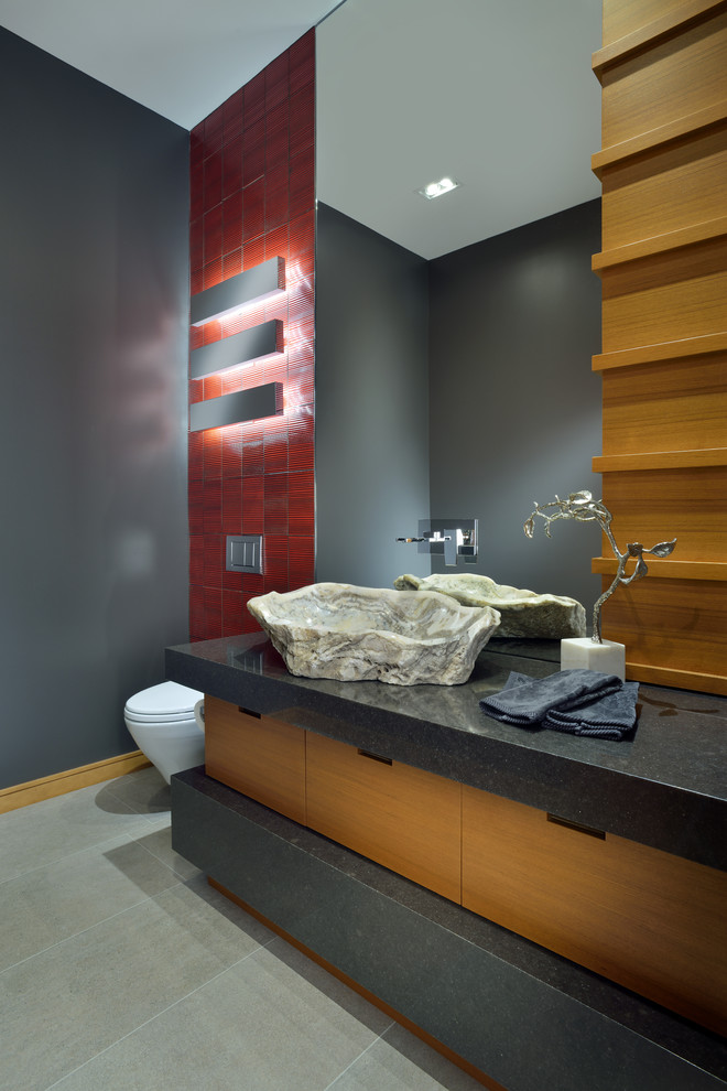Foto på ett stort funkis grå toalett, med ett fristående handfat, släta luckor, skåp i mellenmörkt trä, röd kakel, grå väggar, bänkskiva i kvartsit, en vägghängd toalettstol, keramikplattor och klinkergolv i porslin