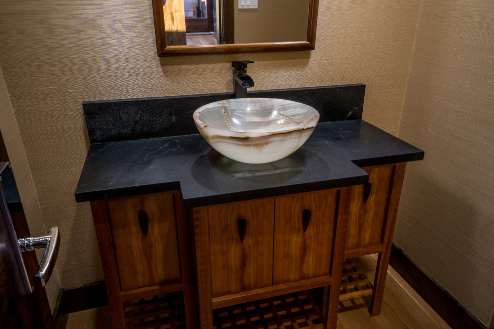 Inspiration för mellanstora asiatiska toaletter, med skåp i mellenmörkt trä, ett fristående handfat, granitbänkskiva och släta luckor