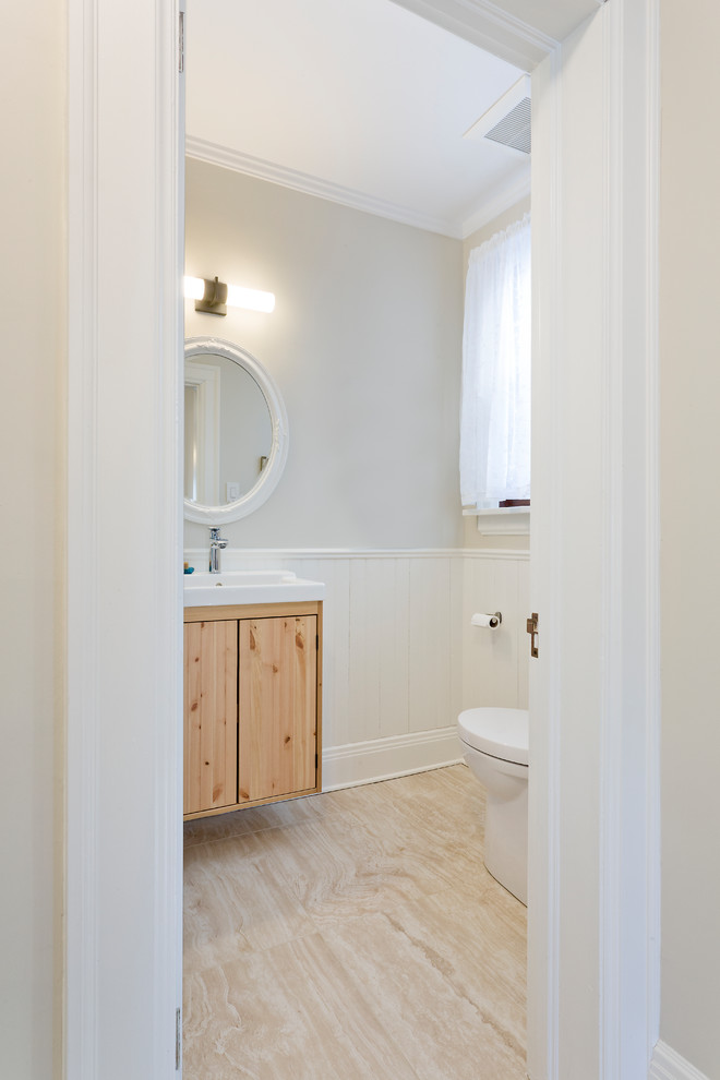 Idées déco pour un petit WC et toilettes craftsman en bois clair avec un placard à porte plane, un mur beige, un sol en carrelage de céramique, un lavabo suspendu et un sol beige.