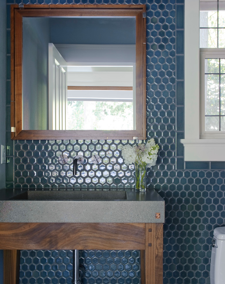Klassisk inredning av ett toalett, med bänkskiva i betong, blå kakel, mosaik och ett integrerad handfat