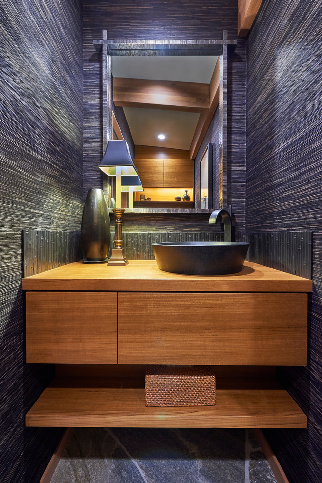 Modelo de aseo clásico renovado con armarios con paneles lisos, puertas de armario de madera oscura, paredes azules, lavabo sobreencimera y encimera de madera