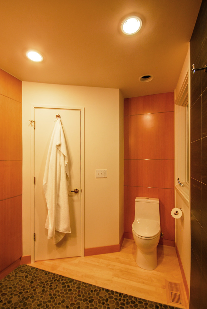 Small contemporary cloakroom in Portland with a one-piece toilet, black tiles, ceramic tiles, white walls, pebble tile flooring, a pedestal sink and brown floors.