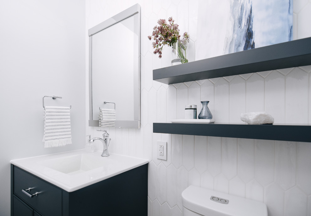 Cette image montre un petit WC et toilettes design avec des portes de placard bleues, WC séparés, un carrelage blanc, des carreaux de céramique, un mur gris, un plan de toilette en quartz modifié, un plan de toilette blanc, un placard à porte plane, un lavabo intégré, un sol en carrelage de porcelaine et un sol gris.