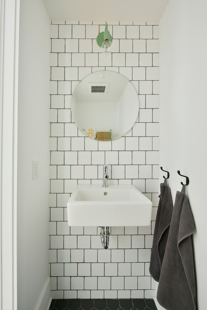 オタワにあるお手頃価格の小さなインダストリアルスタイルのおしゃれなトイレ・洗面所 (白い壁、壁付け型シンク、白いタイル、セラミックタイル、黒い床) の写真