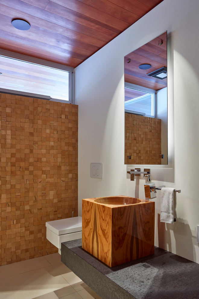 This is an example of a medium sized contemporary cloakroom in San Francisco with a wall mounted toilet, beige tiles and a vessel sink.