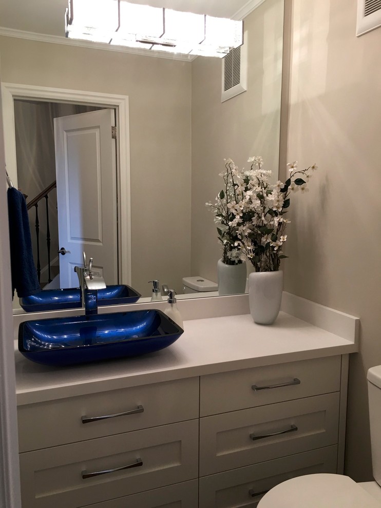 Cette photo montre un WC et toilettes chic avec un placard à porte shaker, des portes de placard blanches, un mur gris, parquet foncé, une vasque et un plan de toilette en quartz modifié.
