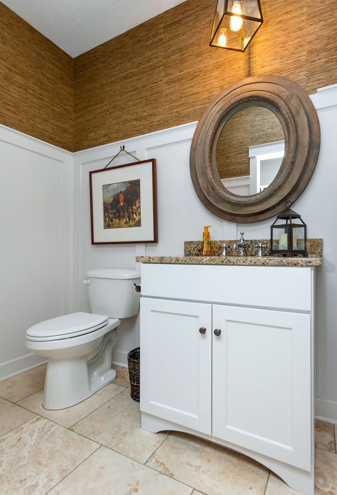 Cette photo montre un petit WC et toilettes craftsman avec un lavabo encastré, un placard à porte plane, des portes de placard blanches, un plan de toilette en granite, WC à poser, un carrelage beige et un sol en travertin.