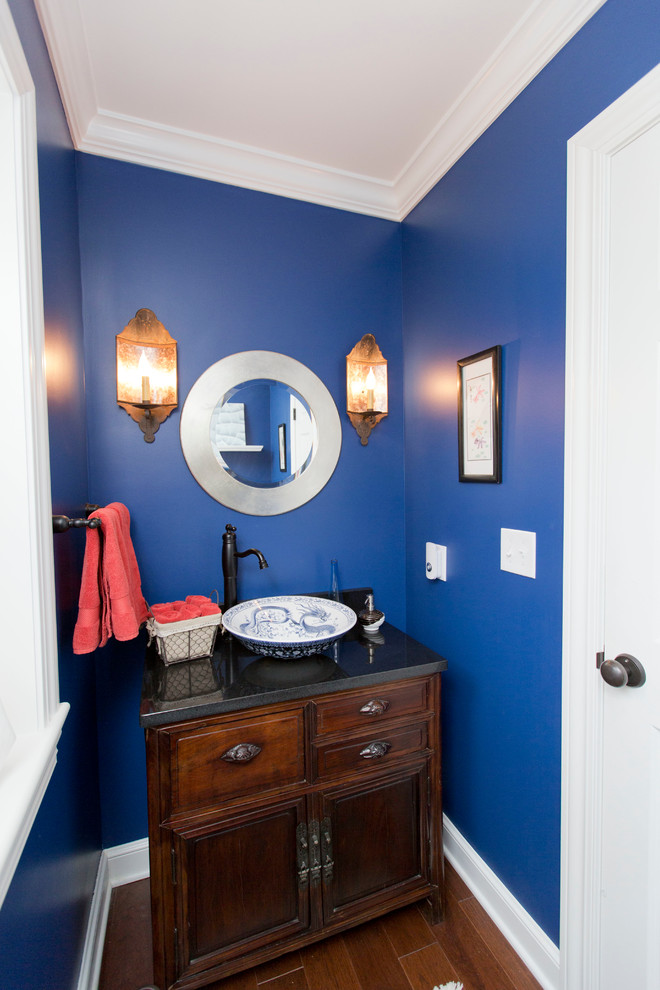 Inspiration for a small eclectic dark wood floor and brown floor powder room remodel in Cleveland with furniture-like cabinets, dark wood cabinets, blue walls, a vessel sink, granite countertops, a two-piece toilet and black countertops