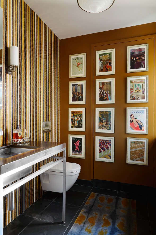 シカゴにあるコンテンポラリースタイルのおしゃれなトイレ・洗面所 (壁掛け式トイレ、マルチカラーの壁、コンソール型シンク、黒い床) の写真