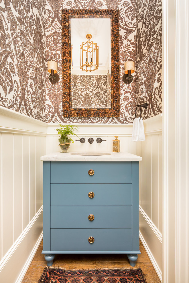 Foto de aseo clásico con armarios con paneles lisos, puertas de armario azules, paredes blancas, suelo de madera en tonos medios y lavabo bajoencimera