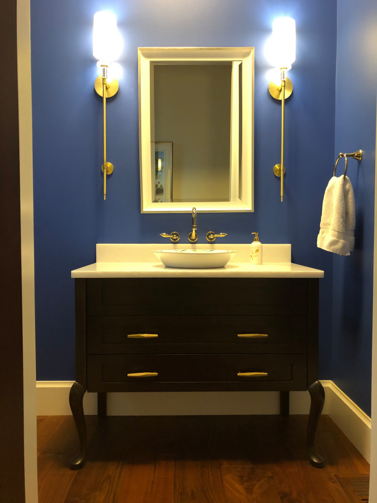 Idee per un bagno di servizio classico con consolle stile comò, ante in legno bruno, pareti blu, pavimento in legno massello medio, top in marmo, pavimento marrone e top bianco