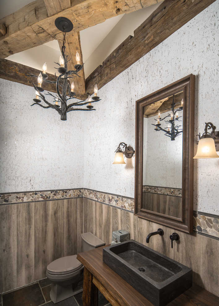 Пример оригинального дизайна: туалет среднего размера в стиле рустика с разноцветной плиткой, галечной плиткой, разноцветными стенами, настольной раковиной, столешницей из дерева и коричневой столешницей