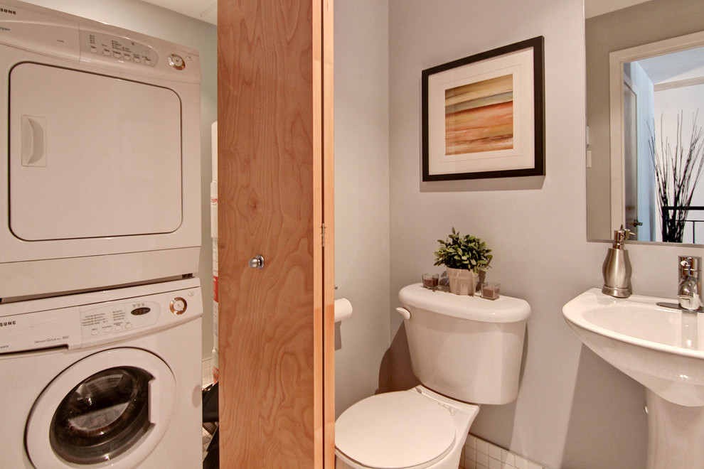 This is an example of a small industrial cloakroom in Montreal with a pedestal sink, a two-piece toilet, white walls and porcelain flooring.