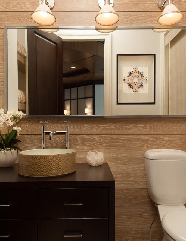 Klassisk inredning av ett mellanstort brun brunt toalett, med ett fristående handfat, släta luckor, skåp i mörkt trä, träbänkskiva, bruna väggar och en toalettstol med separat cisternkåpa