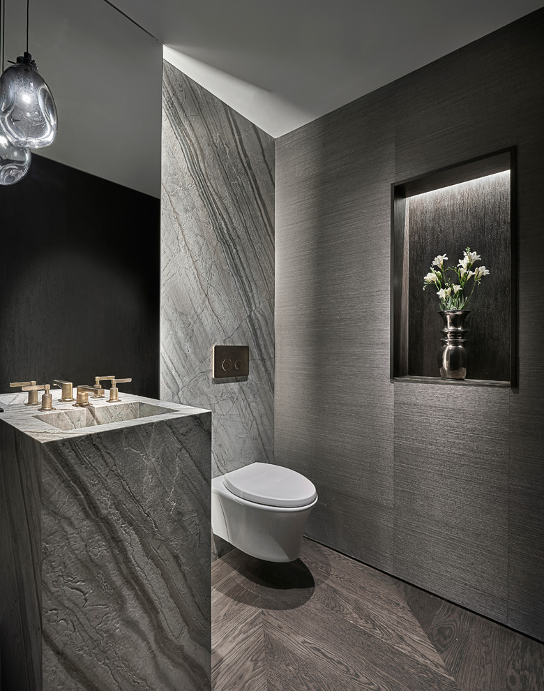 На фото: туалет в современном стиле с серой плиткой, плиткой из листового камня, серыми стенами, раковиной с пьедесталом и коричневым полом с