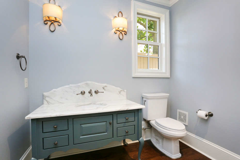 На фото: большой туалет в классическом стиле с врезной раковиной, плоскими фасадами, синими фасадами, мраморной столешницей, раздельным унитазом, белой плиткой, плиткой из листового камня, синими стенами и темным паркетным полом с