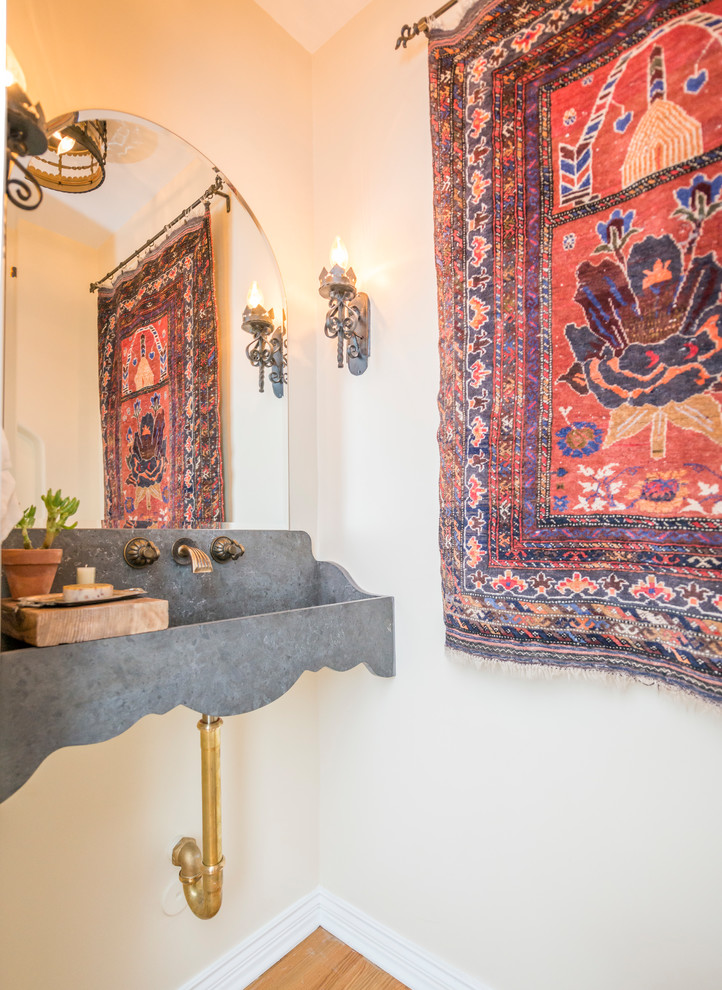 Mediterrane Gästetoilette mit beiger Wandfarbe, braunem Holzboden, Wandwaschbecken und braunem Boden in Los Angeles