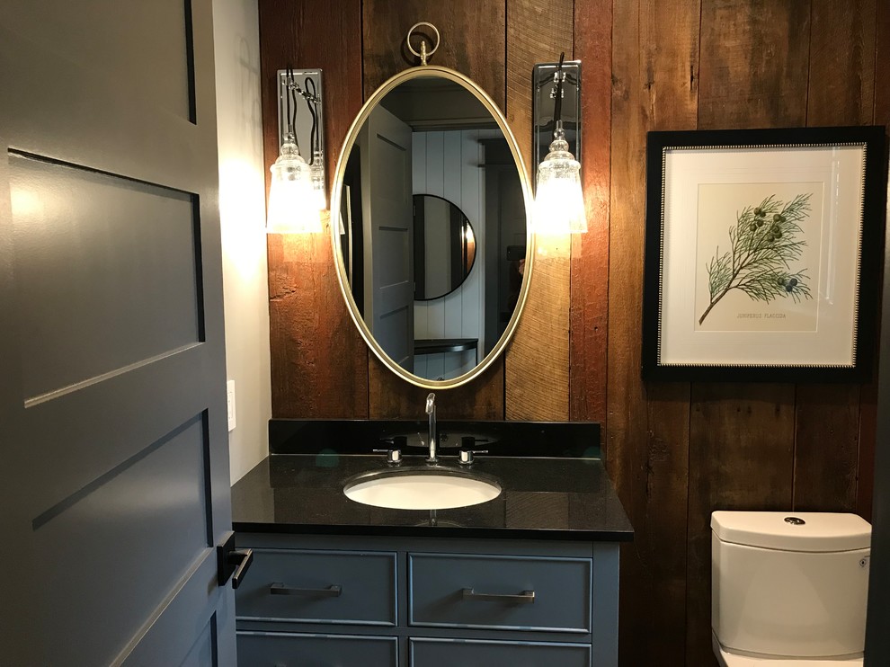 Inspiration for a small rural cloakroom in Philadelphia with freestanding cabinets, grey cabinets, a one-piece toilet, brown walls, dark hardwood flooring, a submerged sink, granite worktops, brown floors and black worktops.
