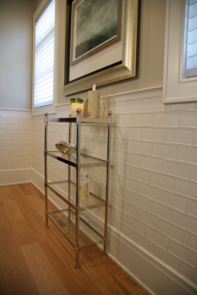 Exempel på ett mellanstort klassiskt brun brunt toalett, med luckor med infälld panel, skåp i mörkt trä, en toalettstol med separat cisternkåpa, vit kakel, keramikplattor, grå väggar, ljust trägolv, ett undermonterad handfat, bänkskiva i onyx och brunt golv