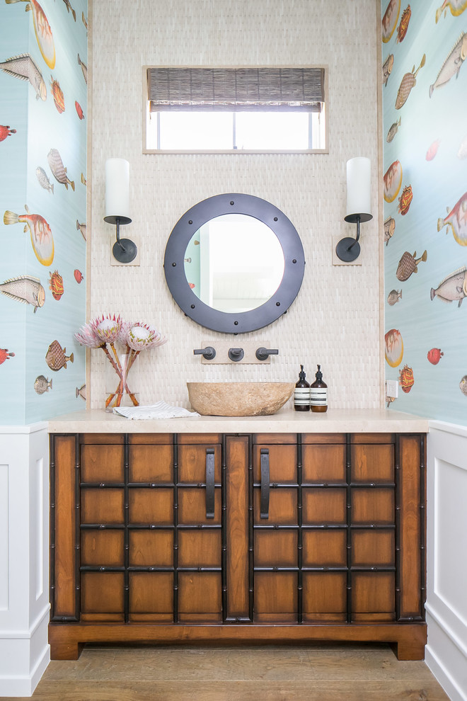 Inspiration for a mid-sized tropical medium tone wood floor and brown floor powder room remodel in Orange County with multicolored walls, a vessel sink, beige countertops, furniture-like cabinets and medium tone wood cabinets