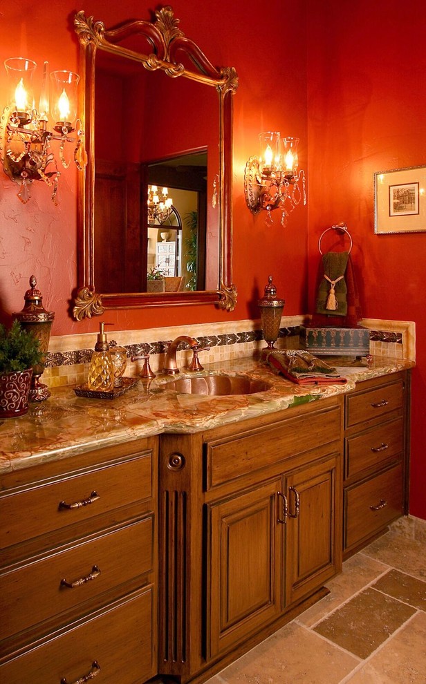 サンフランシスコにあるラグジュアリーな広い地中海スタイルのおしゃれなトイレ・洗面所 (家具調キャビネット、中間色木目調キャビネット、マルチカラーのタイル、赤い壁、トラバーチンの床、オーバーカウンターシンク、クオーツストーンの洗面台) の写真