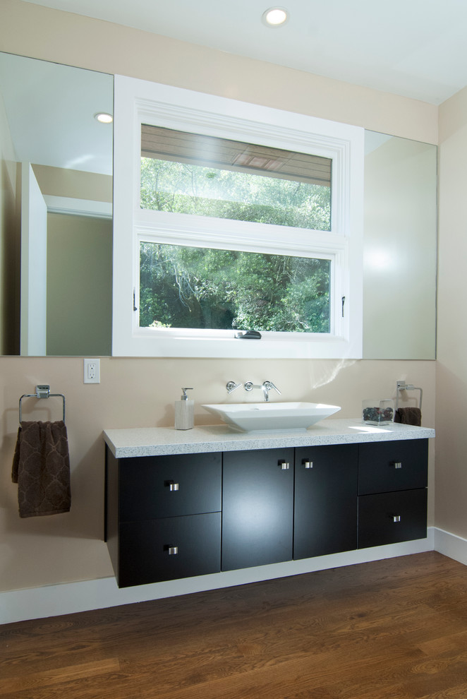 Immagine di un bagno di servizio minimal con lavabo a bacinella, ante lisce, ante in legno bruno, top in quarzo composito e WC monopezzo