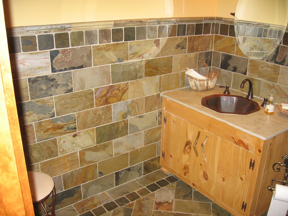На фото: туалет среднего размера в стиле рустика с плоскими фасадами, светлыми деревянными фасадами, плиткой из сланца, разноцветными стенами, полом из сланца, накладной раковиной и разноцветным полом с
