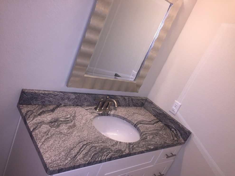 Inredning av ett klassiskt litet grå grått toalett, med skåp i shakerstil, vita skåp, beige väggar, ett undermonterad handfat och granitbänkskiva