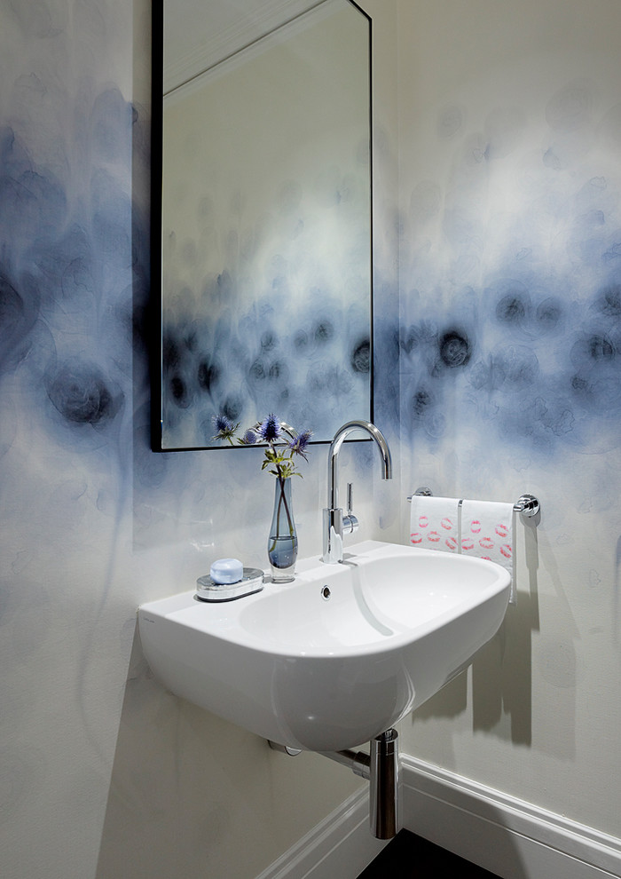 Foto på ett litet funkis toalett, med ett väggmonterat handfat, mörkt trägolv och flerfärgade väggar