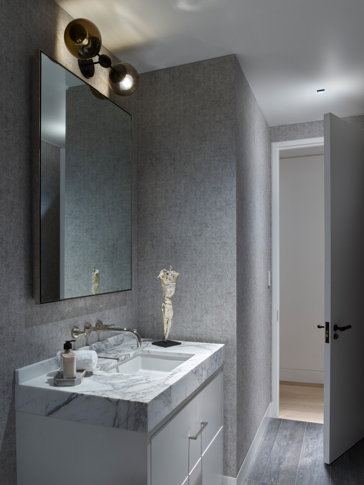 This is an example of a medium sized contemporary cloakroom in San Francisco with flat-panel cabinets, white cabinets, grey walls, marble worktops, grey floors, white worktops and a submerged sink.