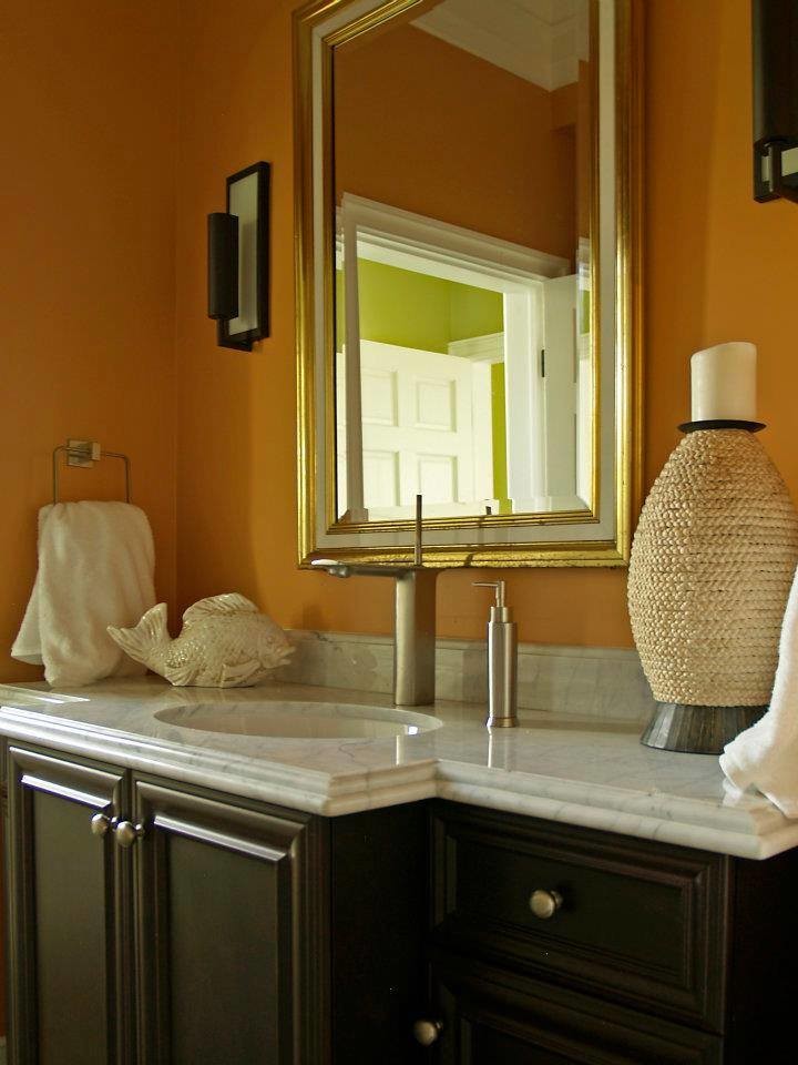Réalisation d'un grand WC et toilettes marin en bois foncé avec un lavabo encastré, un placard en trompe-l'oeil, un plan de toilette en marbre, WC à poser, un carrelage gris, un mur orange et parquet foncé.