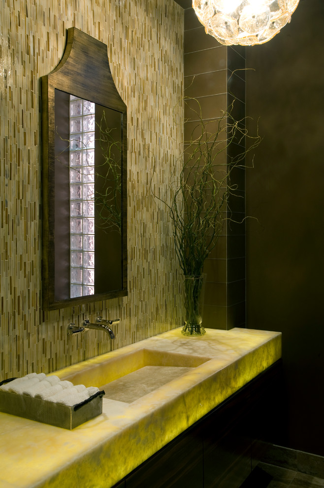 Идея дизайна: маленький туалет в стиле модернизм с монолитной раковиной, столешницей из оникса, удлиненной плиткой, желтыми стенами, бежевой плиткой и желтой столешницей для на участке и в саду
