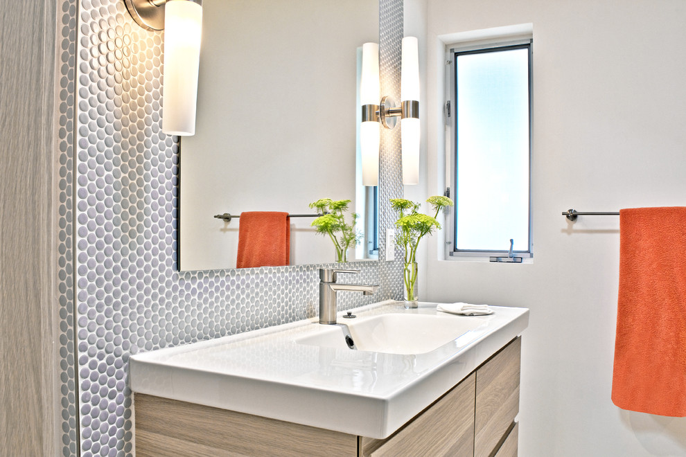 Idee per un piccolo bagno di servizio minimalista con lavabo integrato, ante lisce, ante in legno chiaro, piastrelle a mosaico, pareti bianche e piastrelle grigie