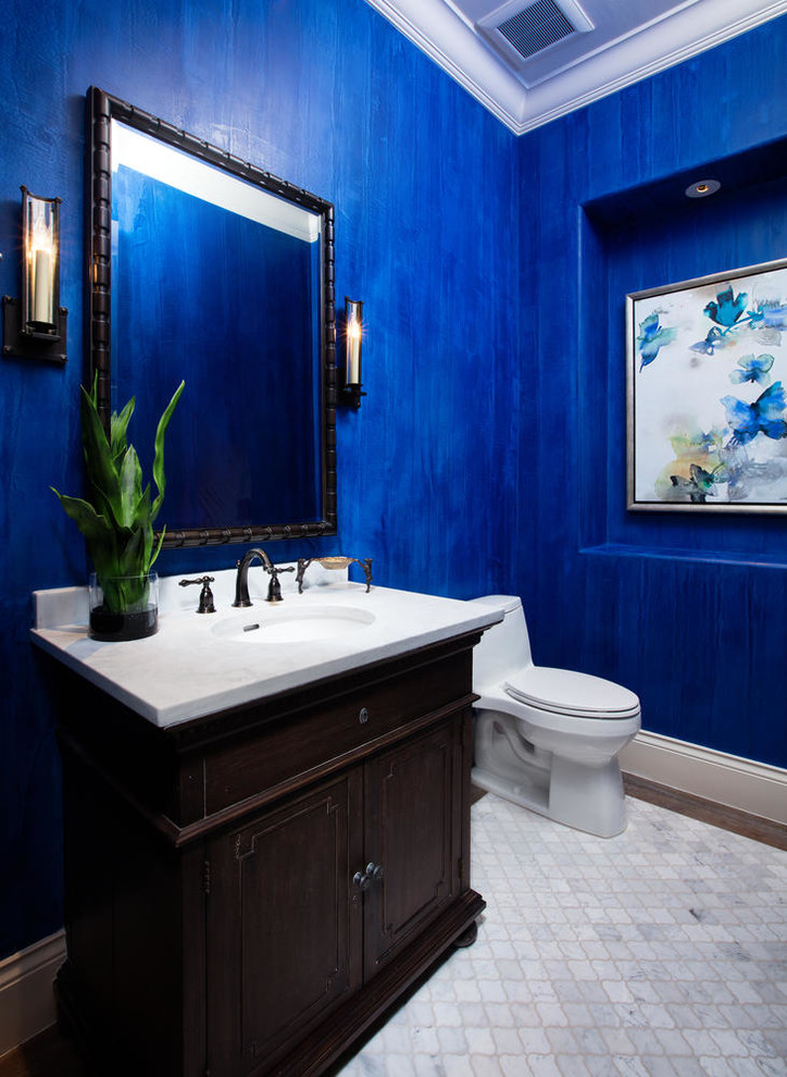 Inspiration for a mediterranean cloakroom with freestanding cabinets, dark wood cabinets, a one-piece toilet, blue walls, a submerged sink and grey floors.